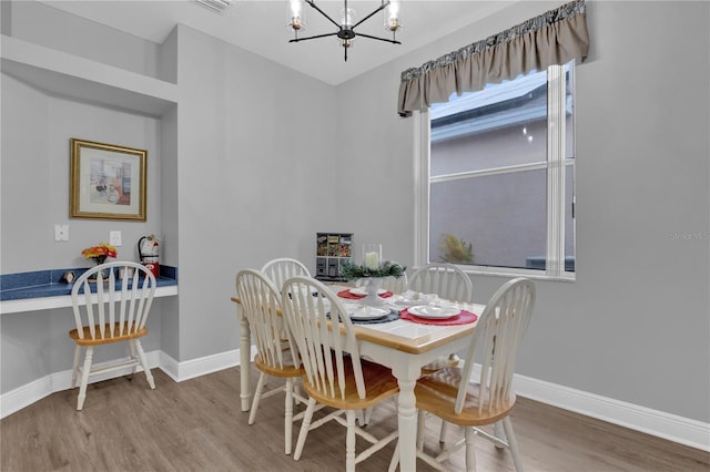 dining area featuring baseboards, a chandelier, and wood finished floors