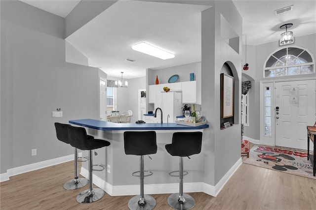 kitchen featuring light wood-style floors, white cabinetry, and a kitchen breakfast bar