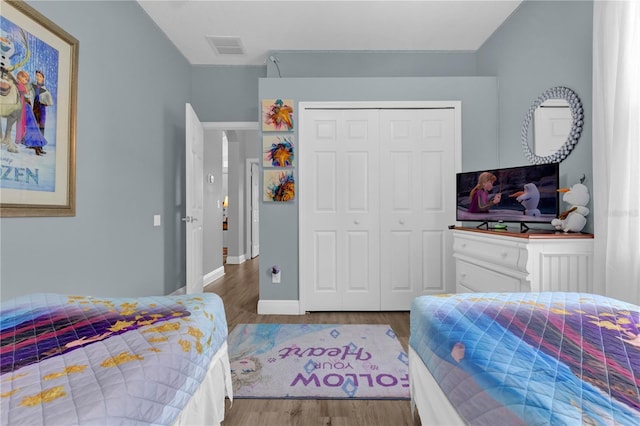 bedroom featuring baseboards, a closet, visible vents, and wood finished floors