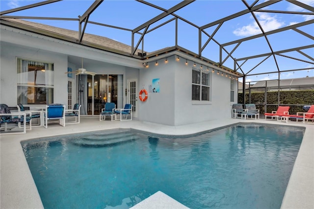 pool with glass enclosure, a patio area, and a ceiling fan