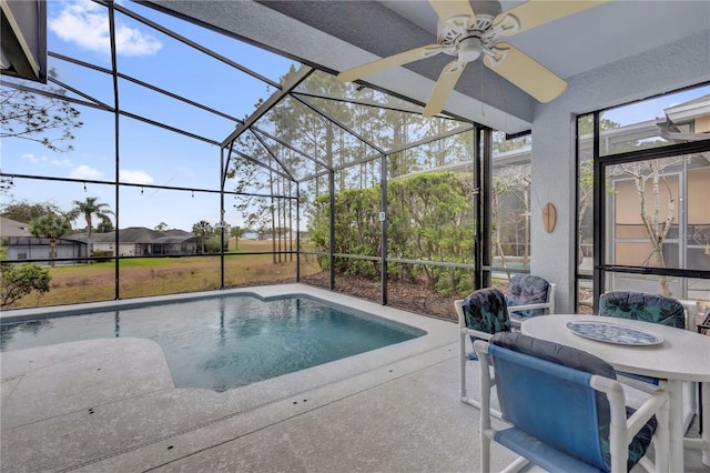 outdoor pool with glass enclosure, a patio area, and a ceiling fan