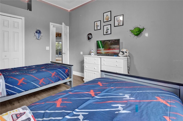 bedroom featuring a closet, baseboards, and dark wood-type flooring