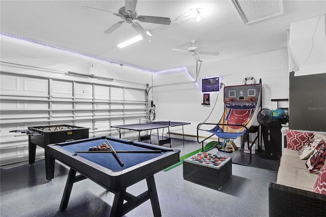 playroom featuring a garage, concrete block wall, a textured ceiling, and speckled floor