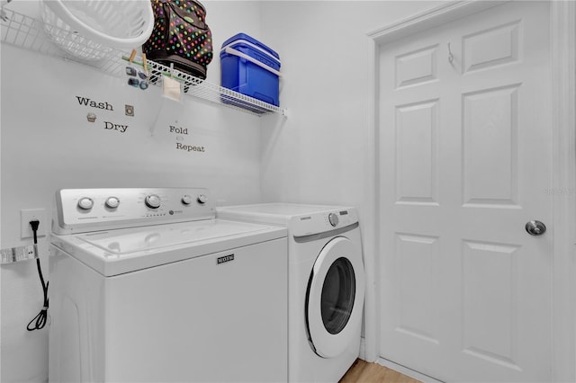 laundry room with light wood-type flooring, washing machine and dryer, and laundry area