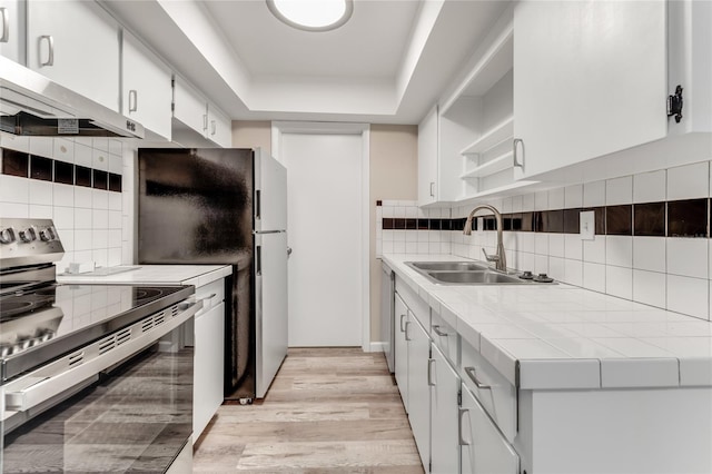 kitchen with tile counters, stainless steel electric range oven, extractor fan, open shelves, and a sink