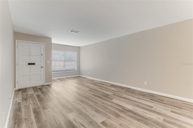 unfurnished room with light wood-style flooring, visible vents, and baseboards