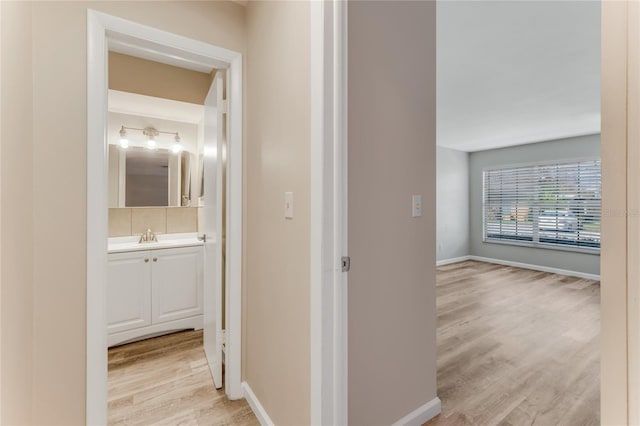 hall with light wood-style flooring and baseboards