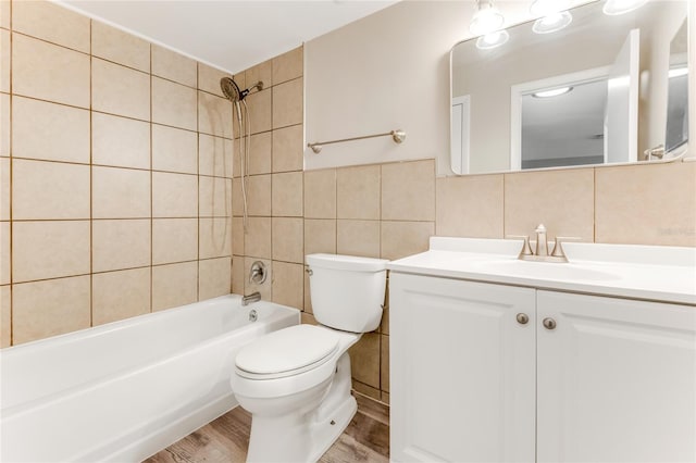 full bath with toilet, shower / bathtub combination, wood finished floors, vanity, and tile walls