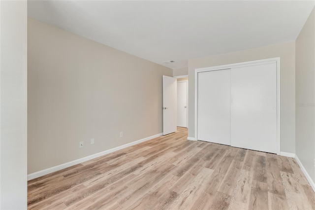 unfurnished bedroom with light wood finished floors, visible vents, baseboards, and a closet