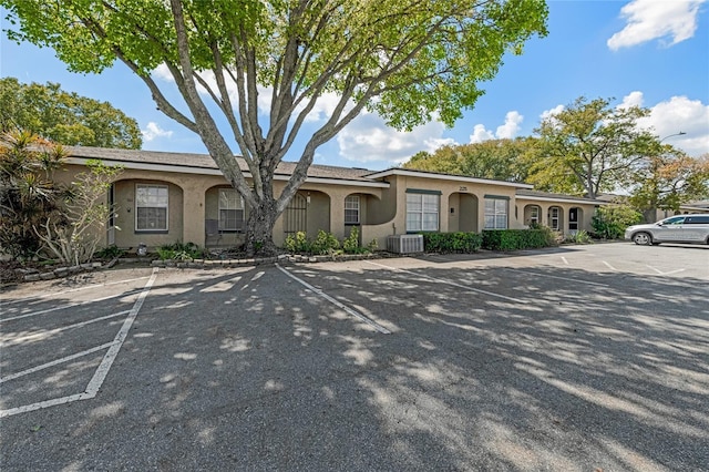 ranch-style house with uncovered parking, cooling unit, and stucco siding