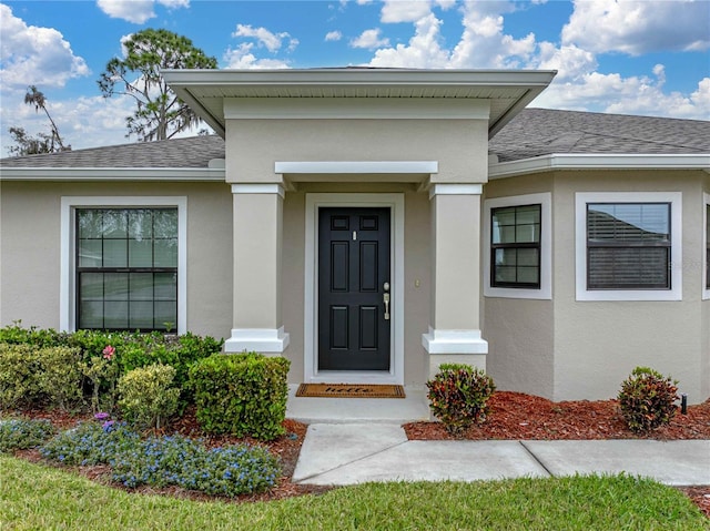 property entrance featuring roof with shingles and stucco siding