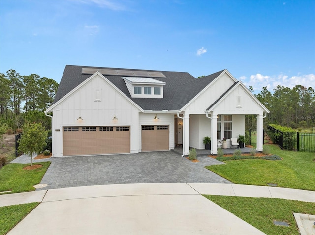 modern farmhouse style home featuring decorative driveway, a porch, board and batten siding, fence, and a front lawn