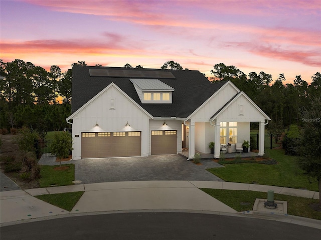 modern inspired farmhouse with an attached garage, fence, decorative driveway, a front lawn, and board and batten siding