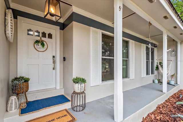 entrance to property with covered porch and stucco siding