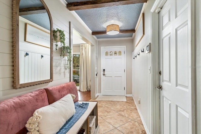 mudroom with crown molding, a textured ceiling, and light tile patterned floors