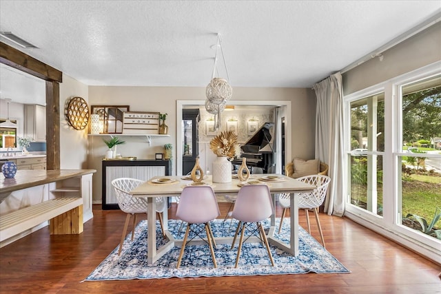 dining area with dark wood-type flooring, a chandelier, visible vents, and a textured ceiling