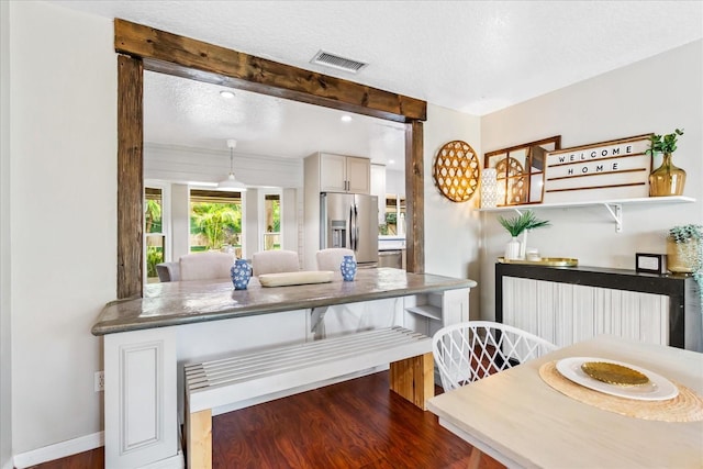 dining room featuring a textured ceiling, visible vents, baseboards, beam ceiling, and dark wood-style floors