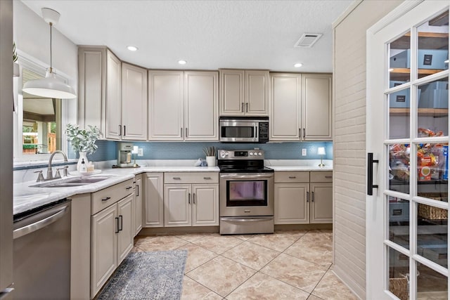 kitchen featuring gray cabinets, light countertops, appliances with stainless steel finishes, light tile patterned flooring, and a sink