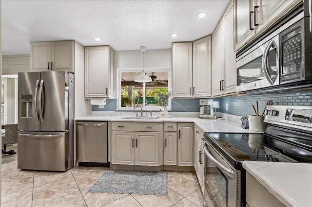 kitchen with a textured ceiling, stainless steel appliances, backsplash, and a sink