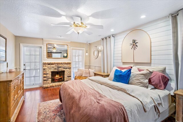 bedroom featuring a textured ceiling, multiple windows, dark wood-style flooring, and a fireplace