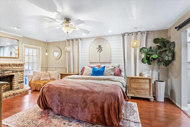 bedroom featuring a fireplace, a textured ceiling, and wood finished floors