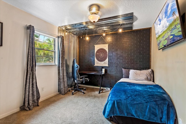 carpeted bedroom with a textured ceiling, brick wall, and baseboards