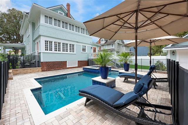 view of pool with a patio area, fence, and a pool with connected hot tub