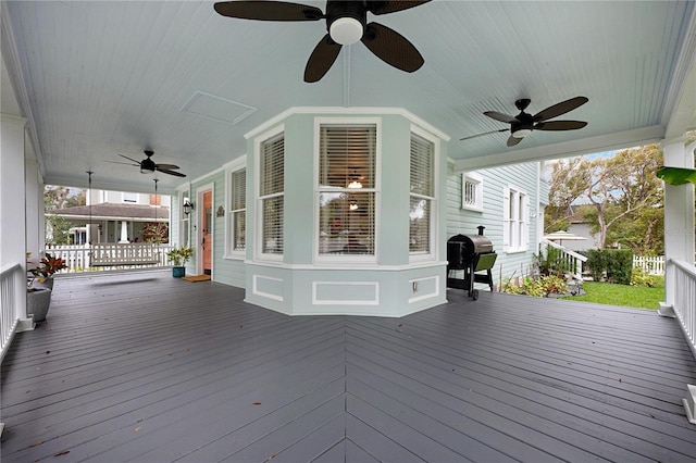 wooden deck with a porch, a ceiling fan, and area for grilling