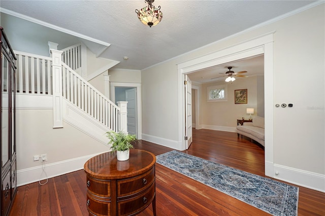 foyer featuring crown molding, a textured ceiling, wood finished floors, baseboards, and stairs