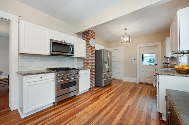 kitchen with stainless steel appliances, white cabinets, hanging light fixtures, and decorative backsplash