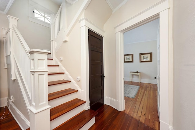 stairway with ornamental molding, baseboards, and wood finished floors