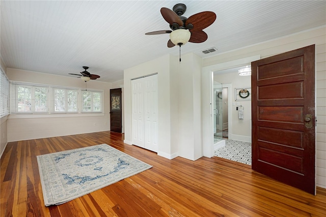 interior space featuring visible vents, ceiling fan, baseboards, and wood finished floors