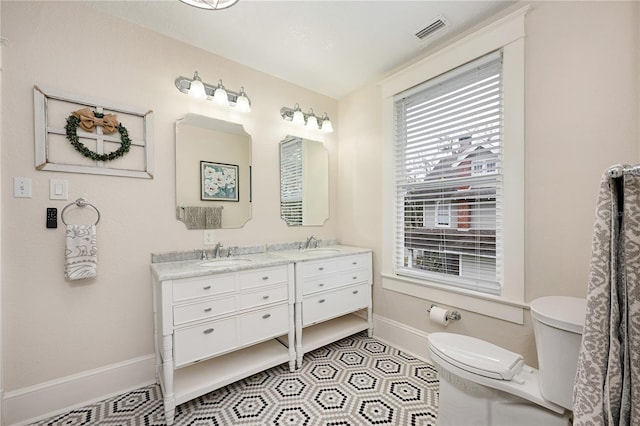 full bath featuring toilet, a sink, visible vents, baseboards, and double vanity