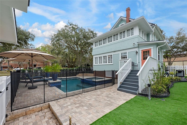 view of pool featuring a fenced backyard, a pool with connected hot tub, stairs, a yard, and a patio area