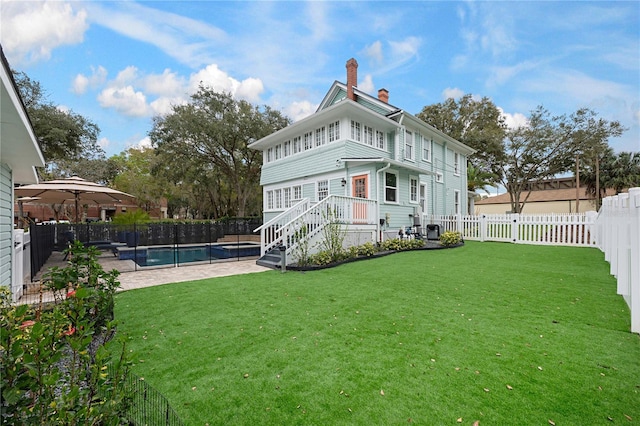 back of house featuring a lawn, a chimney, a fenced backyard, and a fenced in pool