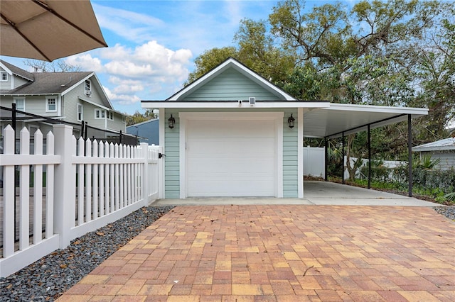 garage with decorative driveway, fence, and a detached garage