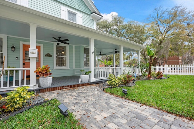 doorway to property featuring a porch, a yard, ceiling fan, and fence