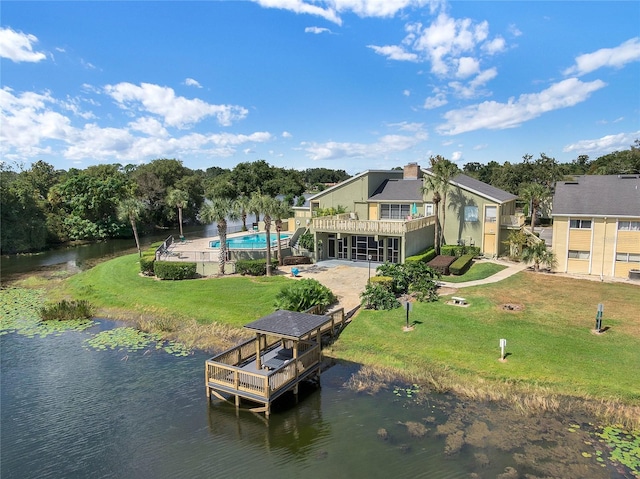 dock area featuring a water view, an outdoor pool, and a yard