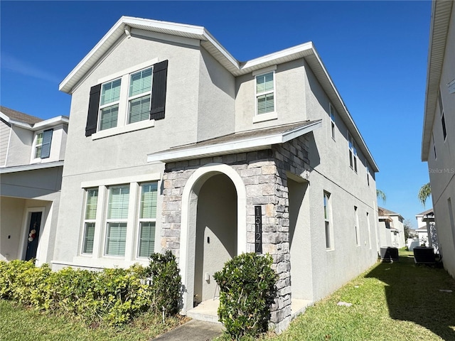 view of front of house featuring stone siding, central air condition unit, and stucco siding