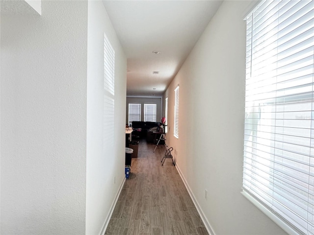 corridor with baseboards and wood finished floors