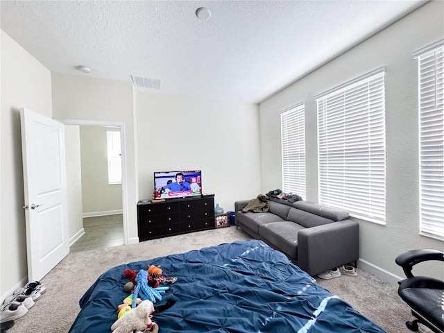 carpeted bedroom with visible vents, a textured ceiling, and baseboards