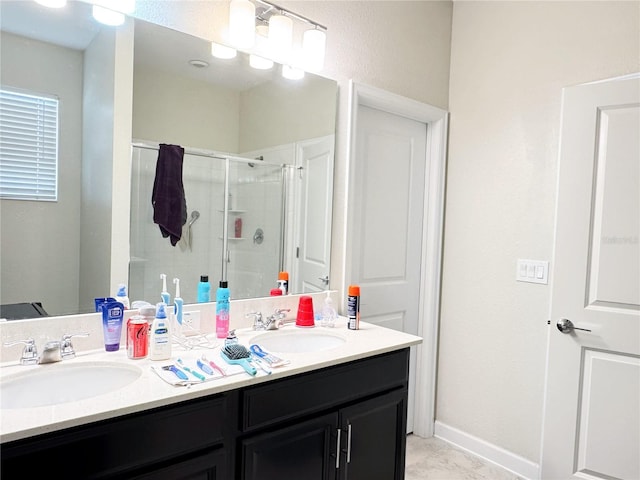 full bathroom featuring baseboards, double vanity, a sink, and a shower stall