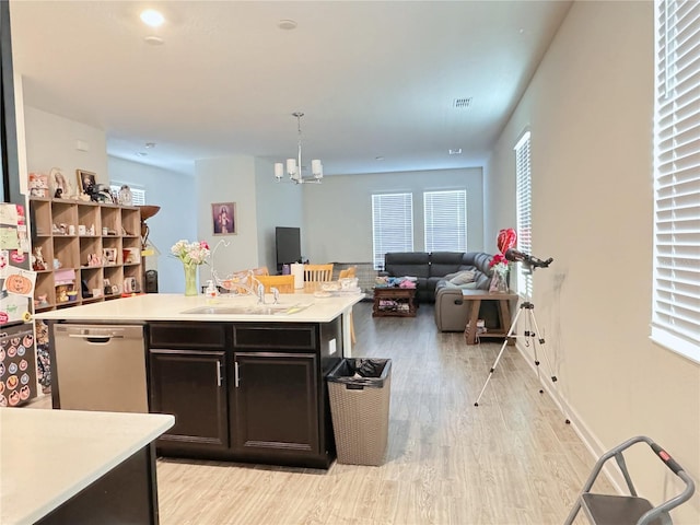 kitchen featuring a kitchen island with sink, a sink, open floor plan, light countertops, and stainless steel dishwasher