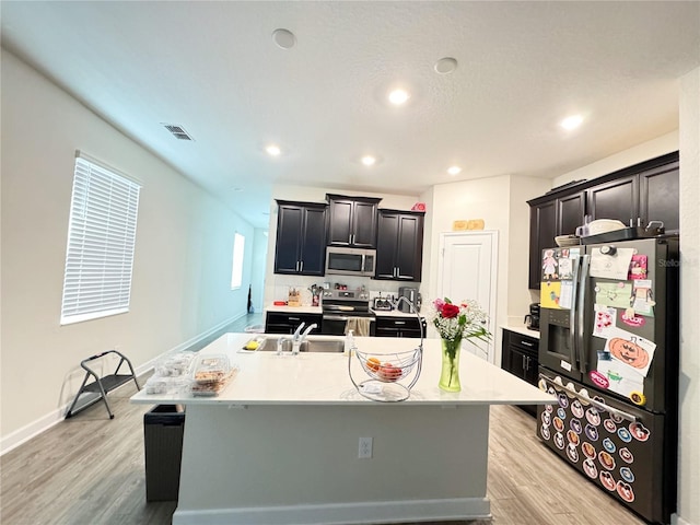 kitchen featuring a center island with sink, light countertops, visible vents, appliances with stainless steel finishes, and a sink