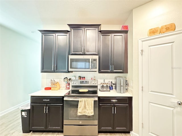 kitchen with tasteful backsplash, baseboards, light wood-style flooring, stainless steel appliances, and light countertops