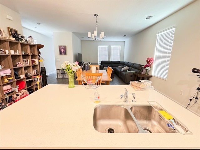 kitchen featuring visible vents, open floor plan, hanging light fixtures, a chandelier, and a sink