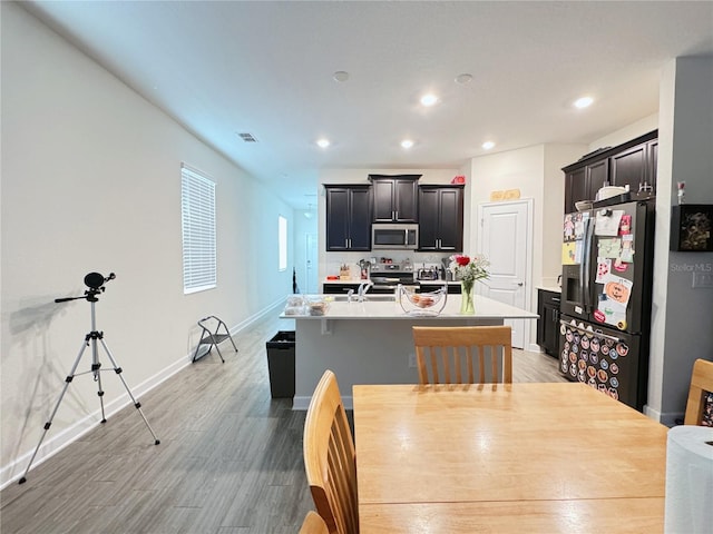 kitchen with a kitchen island with sink, a sink, visible vents, light countertops, and appliances with stainless steel finishes