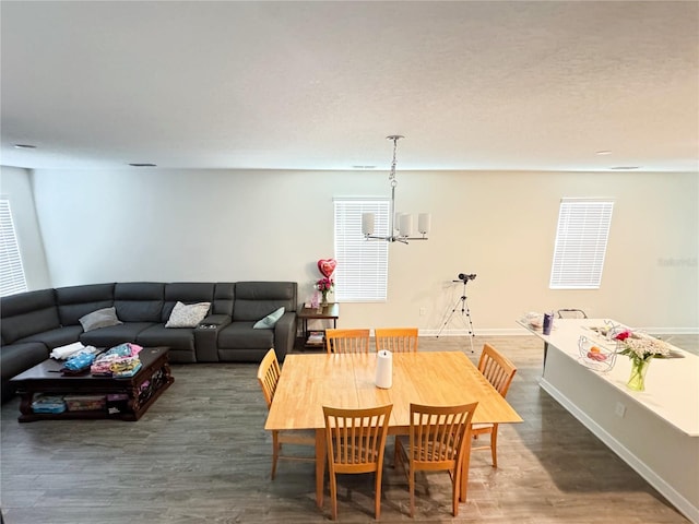 dining room featuring a chandelier, dark wood-style flooring, baseboards, and a healthy amount of sunlight