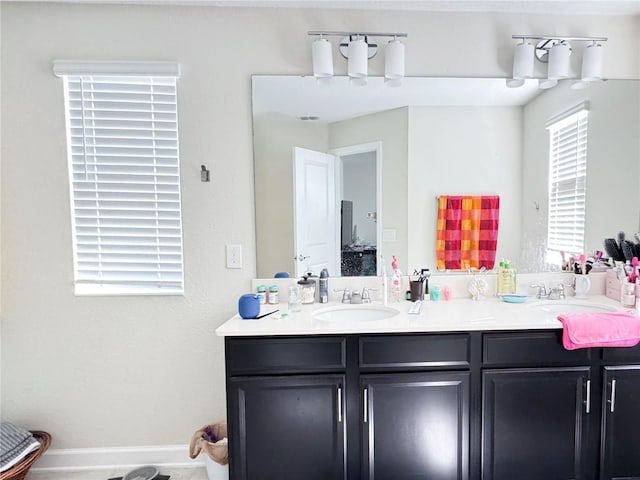 bathroom featuring double vanity, baseboards, and a sink