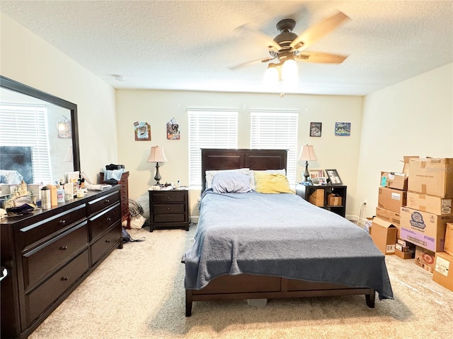 bedroom with a ceiling fan, a textured ceiling, and light colored carpet